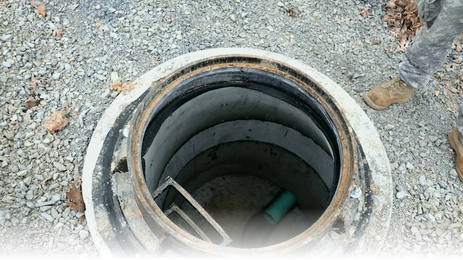 Close-up of a precast concrete manhole frame with the cast-iron cover removed, photographed during a Ft. Indiantown Gap, Pennsylvania sewer-line replacement project — exactly the type of structure where a Cretex chimney seal installs